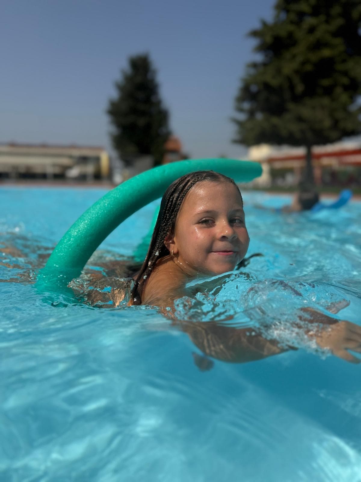 Nena nedant a la piscina amb un xurro