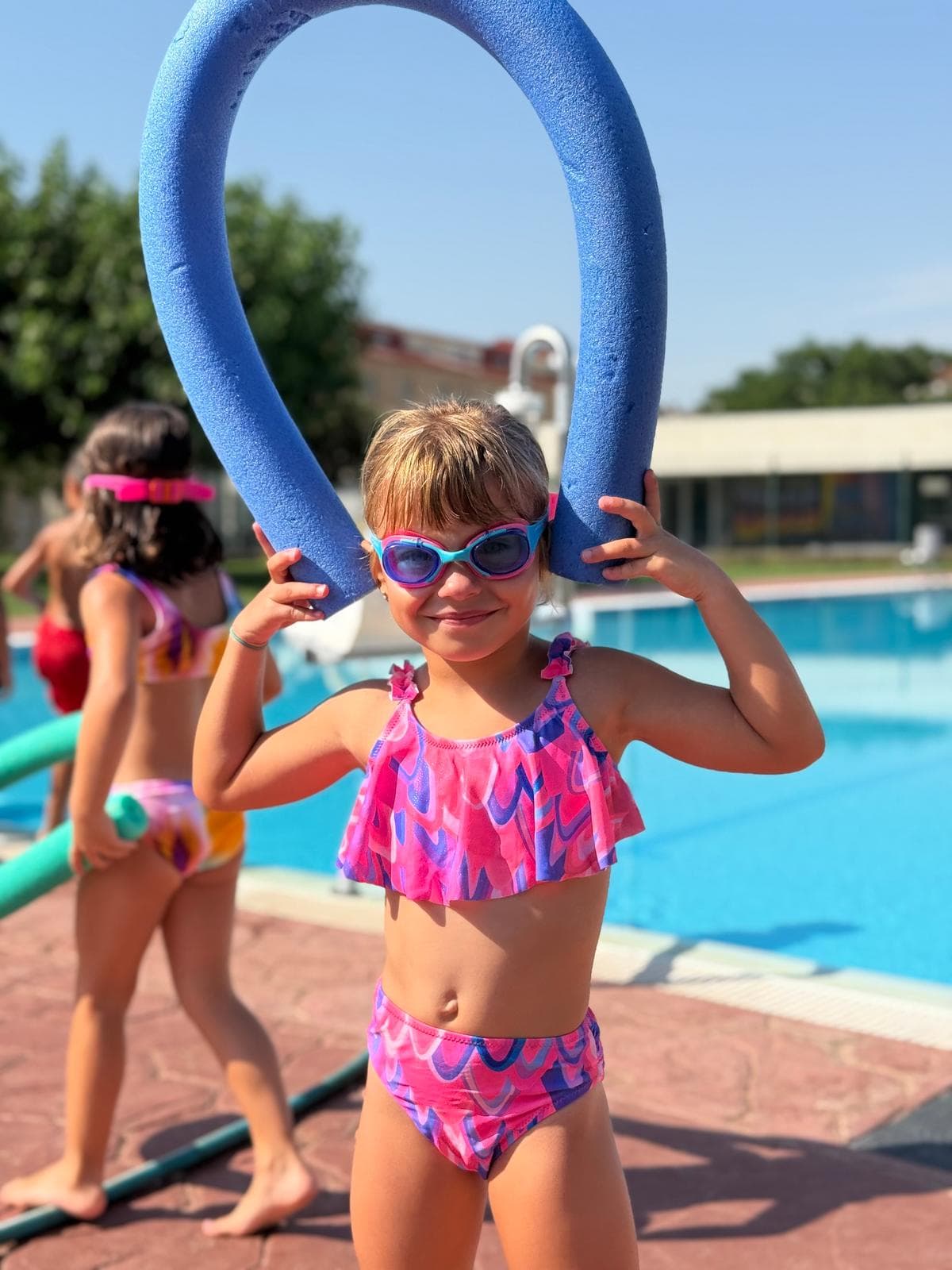 Nena amb ulleres de busseig i xurro a la piscina