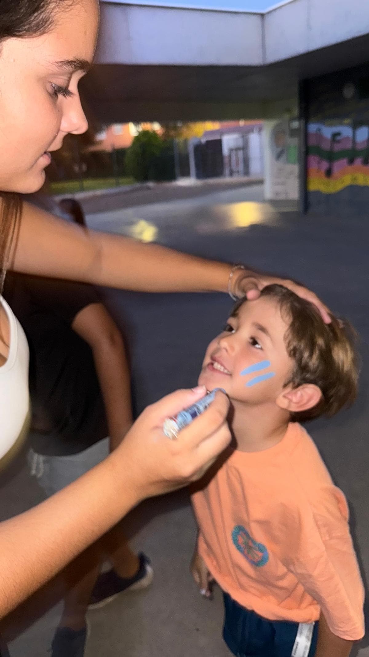 Monitora pintant la cara a un nen
